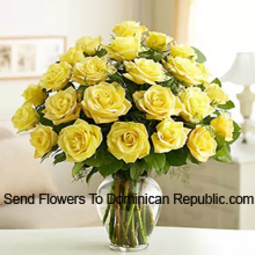 24 Roses jaunes divines avec quelques fougères dans un vase en verre